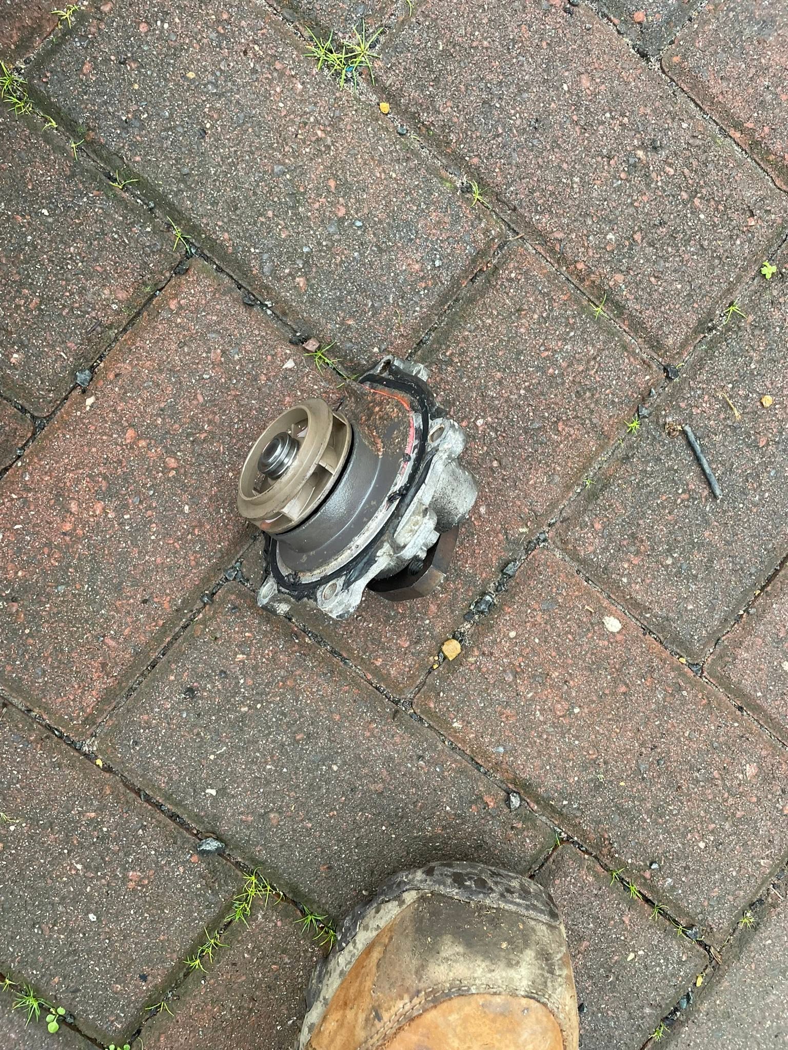 A removed water pump lying on block paving