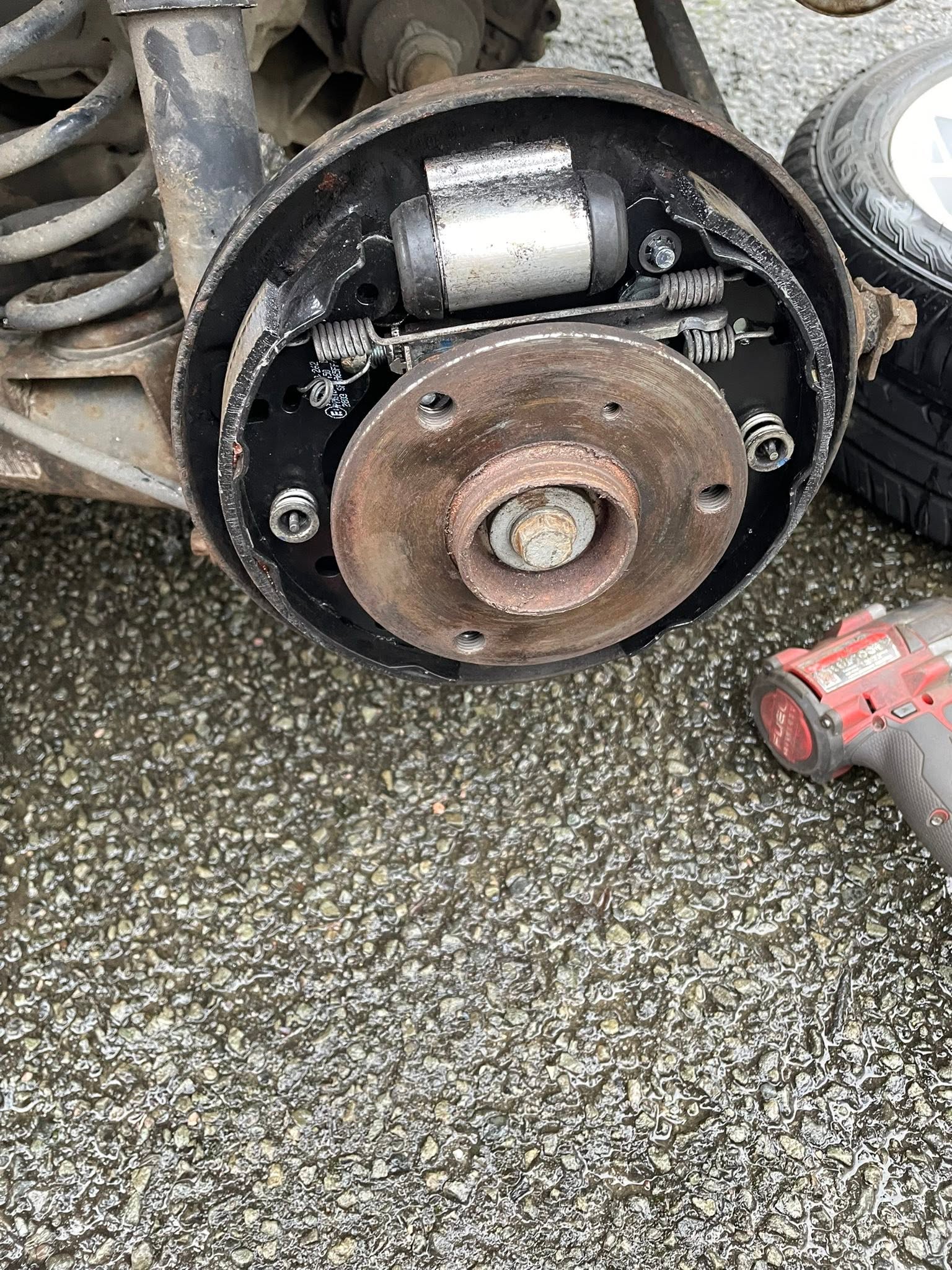 Rear drum brake stripped down with the wheel off, impact gun beside it